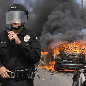 Los Angeles Police Department commander Cory Palka stands among several destroyed police cars...webp