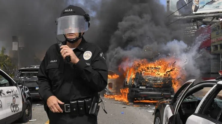 Los Angeles Police Department commander Cory Palka stands among several destroyed police cars...webp
